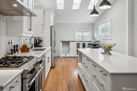 a kitchen with a stove a sink and wooden floor