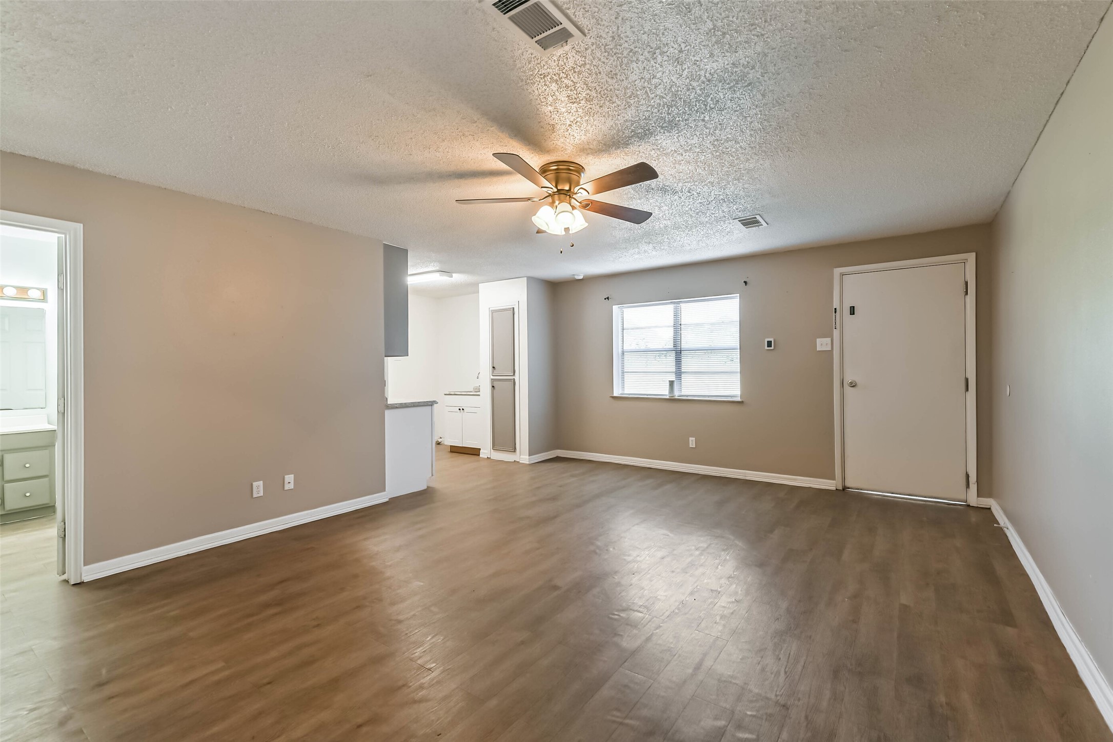 4869 Fm 2518 Cleveland, TX 77327 - Photo 15 of 41 an empty room with wooden floor ceiling fan and windows