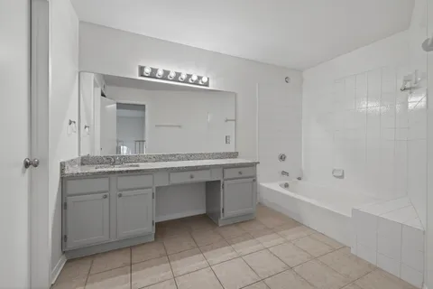 a spacious bathroom with a granite countertop sink mirror and bathtub
