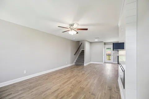 a view of an empty room with wooden floor and chandelier