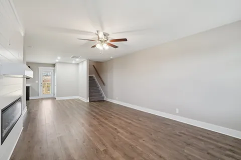 an empty room with wooden floor fireplace and windows