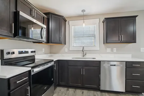 a large kitchen with a sink stainless steel appliances and cabinets