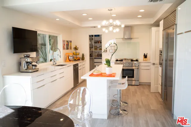 a kitchen that has a lot of white cabinets and stainless steel appliances