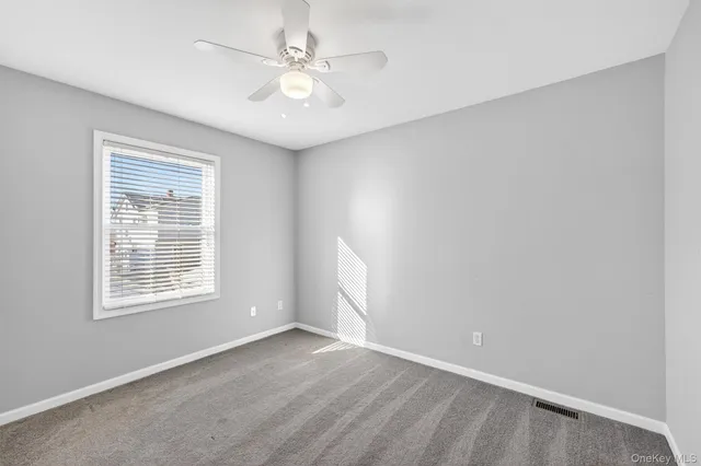 an empty room with chandelier fan and windows