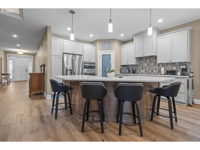 a kitchen with stainless steel appliances kitchen island granite countertop a table chairs sink and cabinets
