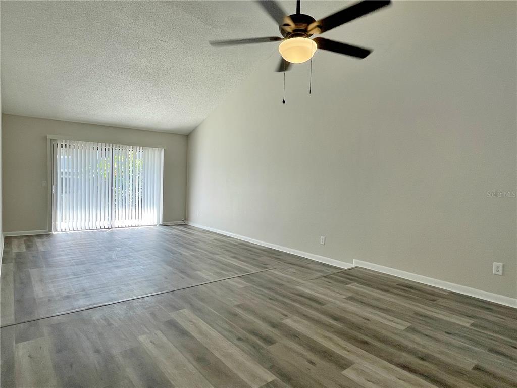 702 St Matthew Circle Altamonte Springs, FL 32714 - Photo 7 of 27 an empty room with wooden floor fan and windows