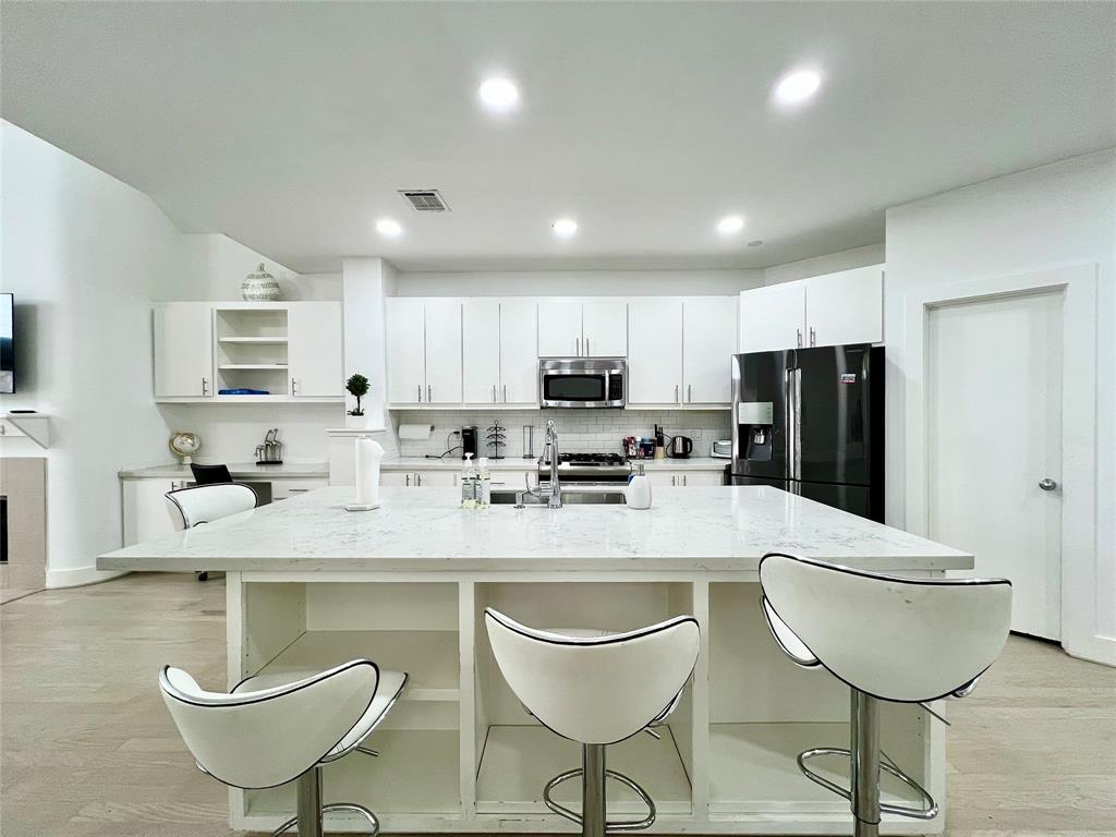 a kitchen with stainless steel appliances granite countertop a stove a refrigerator a sink a dining table and chairs
