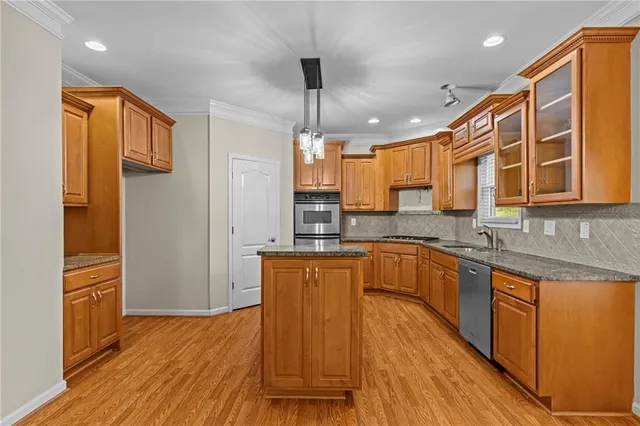 a kitchen with stainless steel appliances granite countertop wooden cabinets a refrigerator a sink a stove and a wooden floors