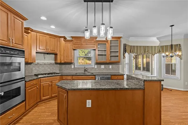 a kitchen with kitchen island granite countertop a sink cabinets and stainless steel appliances