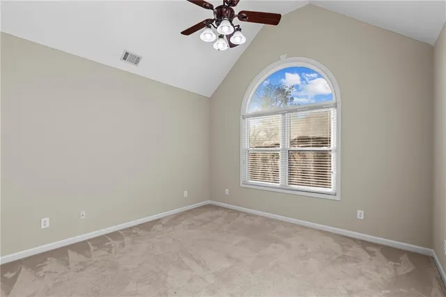 an empty room with chandelier fan and windows
