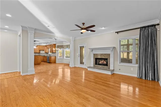 a view of a livingroom with a fireplace a ceiling fan and wooden floor