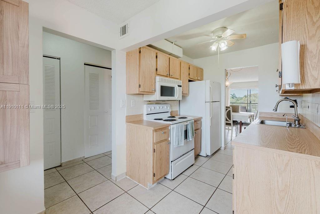 3110 North Pine Island Road, Unit 409 Sunrise, FL 33351 - Photo 4 of 18 a kitchen with white cabinets and appliances