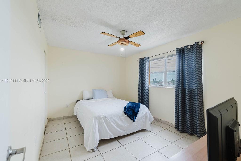 3110 North Pine Island Road, Unit 409 Sunrise, FL 33351 - Photo 8 of 18 a bedroom with a bed and a ceiling fan
