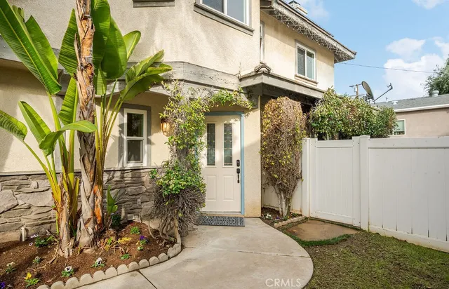 a view of a white house with large windows and potted plants