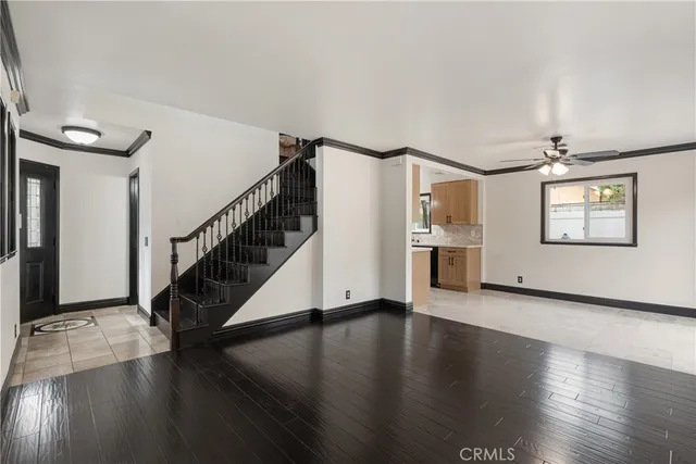 a view of a livingroom with wooden floor staircase and a kitchen