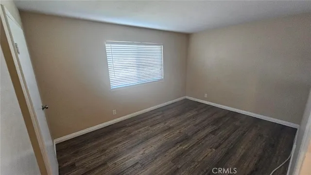 an empty room with wooden floor and window