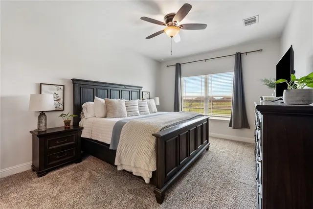 a spacious bedroom with a bed and a flat screen tv