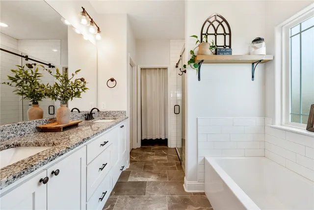 a bathroom with a granite countertop tub sink and mirror