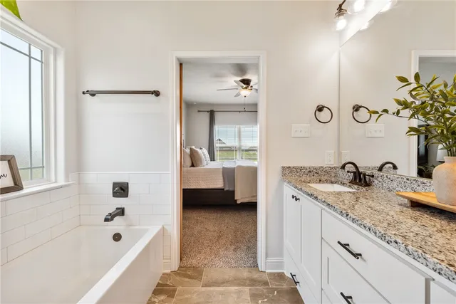 a en suite spacious bathroom with a granite countertop tub sink and mirror