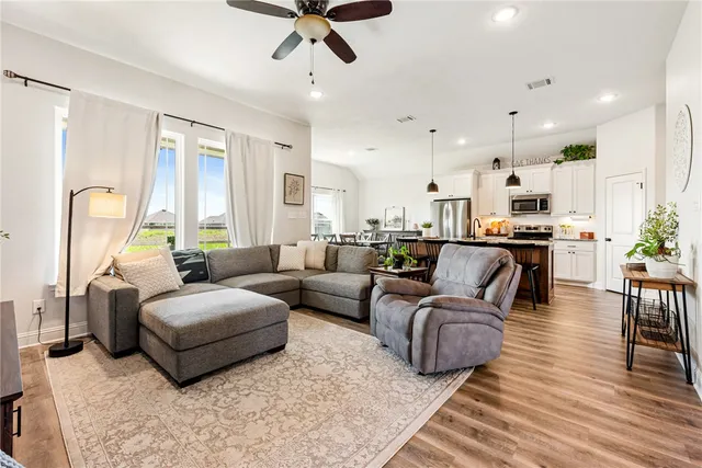 a living room with furniture kitchen view and a wooden floor