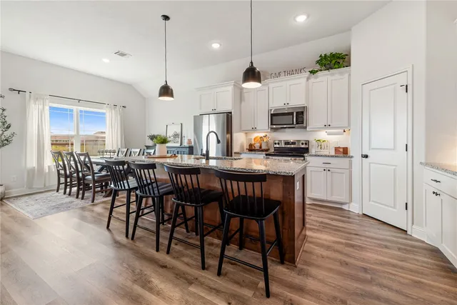 a kitchen with stainless steel appliances granite countertop a stove a refrigerator a kitchen island a sink and a refrigerator