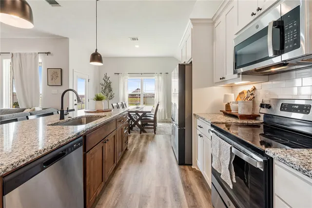 a kitchen with stainless steel appliances granite countertop a sink a stove microwave and cabinets