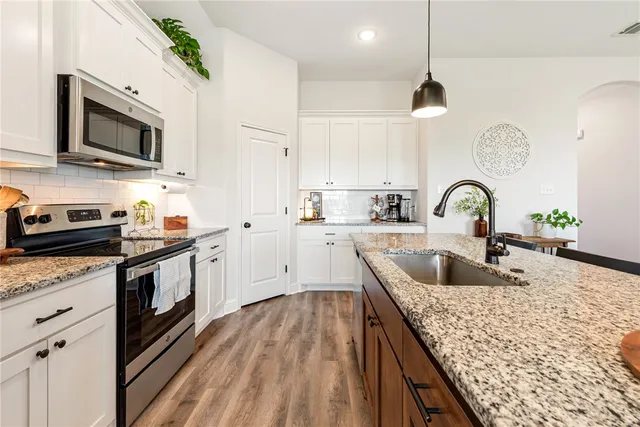 a kitchen with stainless steel appliances granite countertop a sink a stove and a microwave
