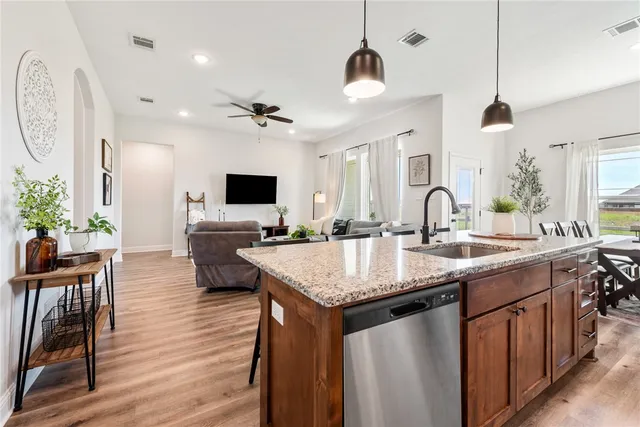 a kitchen with stainless steel appliances granite countertop a sink a stove and a wooden floors
