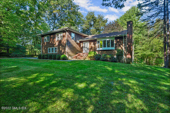 a view of a house next to a big yard with large trees