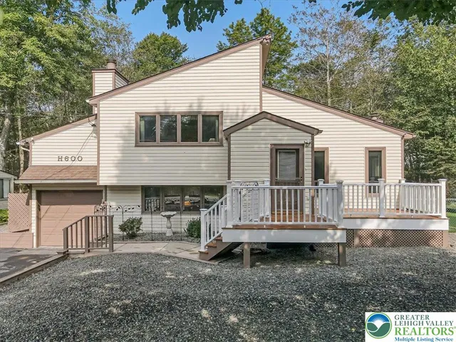 a view of a white house next to a yard and large trees