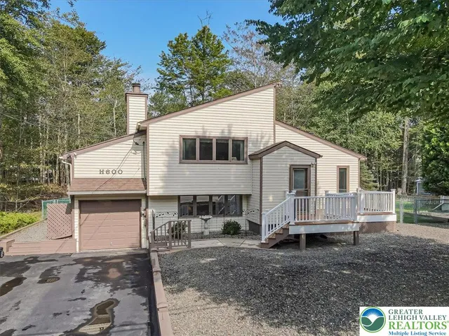 a view of a white house next to a yard and large trees