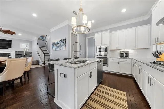 a kitchen that has a lot of white cabinets and stainless steel appliances
