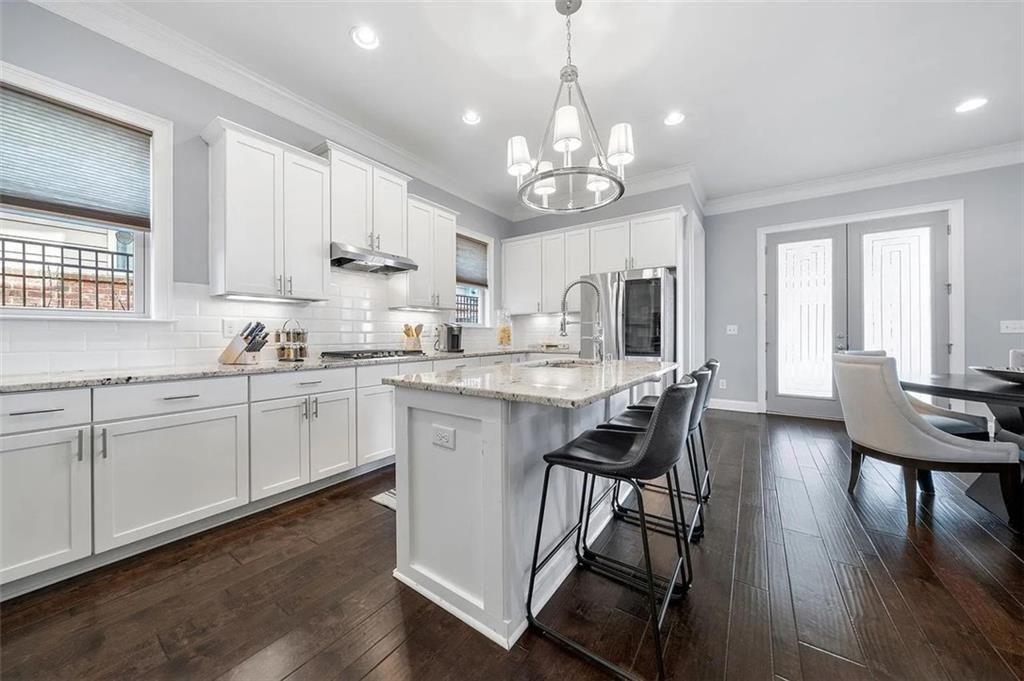 3165 Oakdale Road Atlanta, GA 30354 - Photo 5 of 35 a kitchen with stainless steel appliances granite countertop a stove top oven a sink dishwasher a dining table and chairs with wooden floor