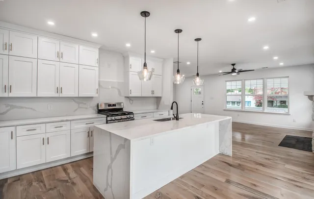 a kitchen with stainless steel appliances granite countertop a sink a stove and a wooden floors