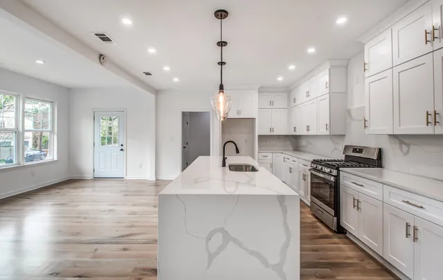 a kitchen with kitchen island granite countertop a sink a counter space appliances and cabinets