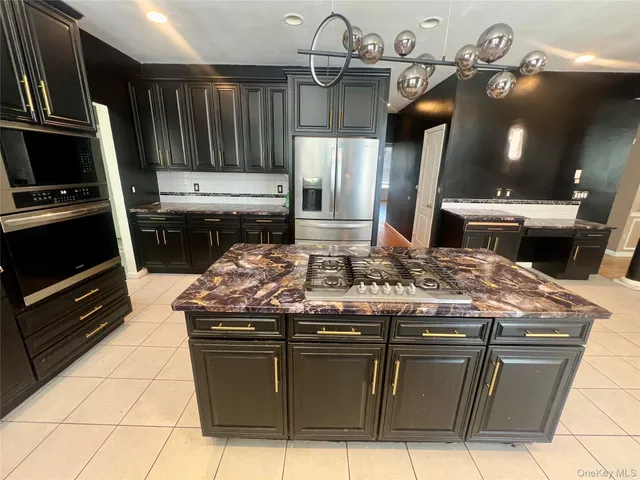 a large kitchen with kitchen island granite countertop a large counter top stainless steel appliances and cabinets