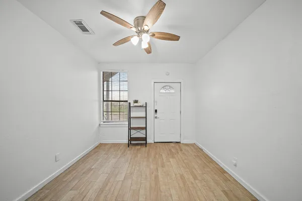 an empty room with wooden floor and windows