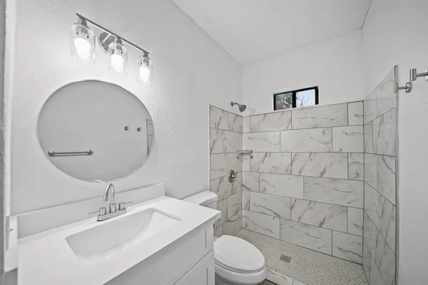a bathroom with a toilet sink a mirror and shower