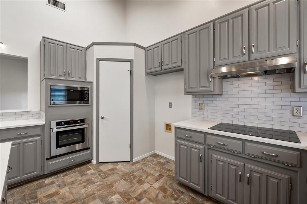 1036 Clinton Street Carrollton, TX 75007 - Photo 18 of 40 Kitchen featuring gray cabinetry, backsplash, stainless steel appliances, and under cabinet range hood