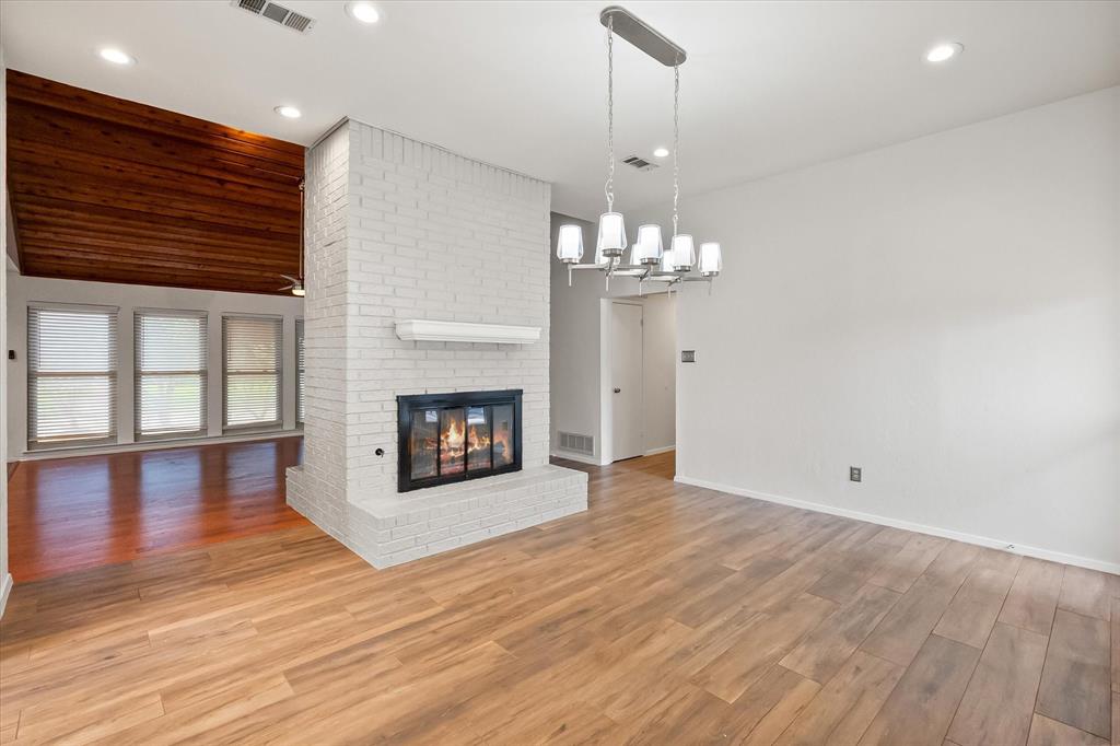 1036 Clinton Street Carrollton, TX 75007 - Photo 20 of 40 Unfurnished living room with wood finished floors, a brick fireplace, a chandelier, and recessed lighting