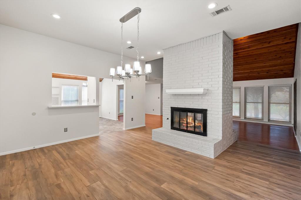 1036 Clinton Street Carrollton, TX 75007 - Photo 21 of 40 Unfurnished living room with a chandelier, wood finished floors, a fireplace, recessed lighting, and vaulted ceiling