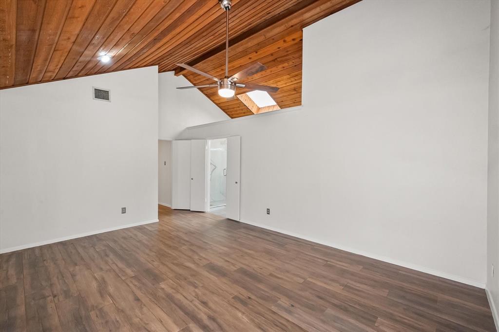 1036 Clinton Street Carrollton, TX 75007 - Photo 25 of 40 Unfurnished living room featuring ceiling fan, dark wood finished floors, high vaulted ceiling, a skylight, and wood ceiling