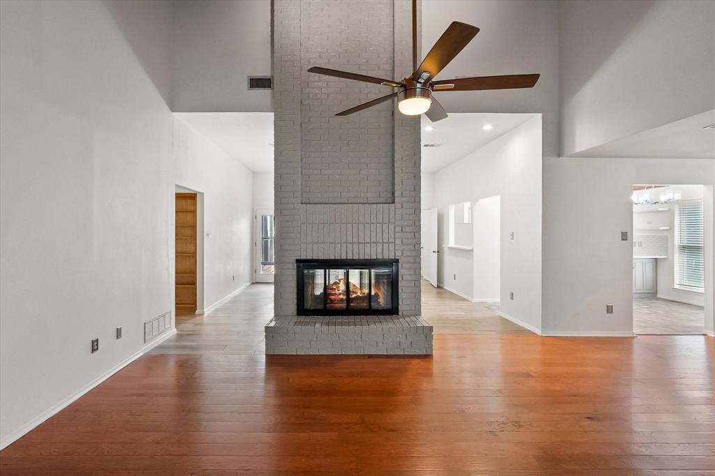 1036 Clinton Street Carrollton, TX 75007 - Photo 6 of 40 Unfurnished living room with high vaulted ceiling, a fireplace, light wood-style floors, healthy amount of natural light, and ceiling fan