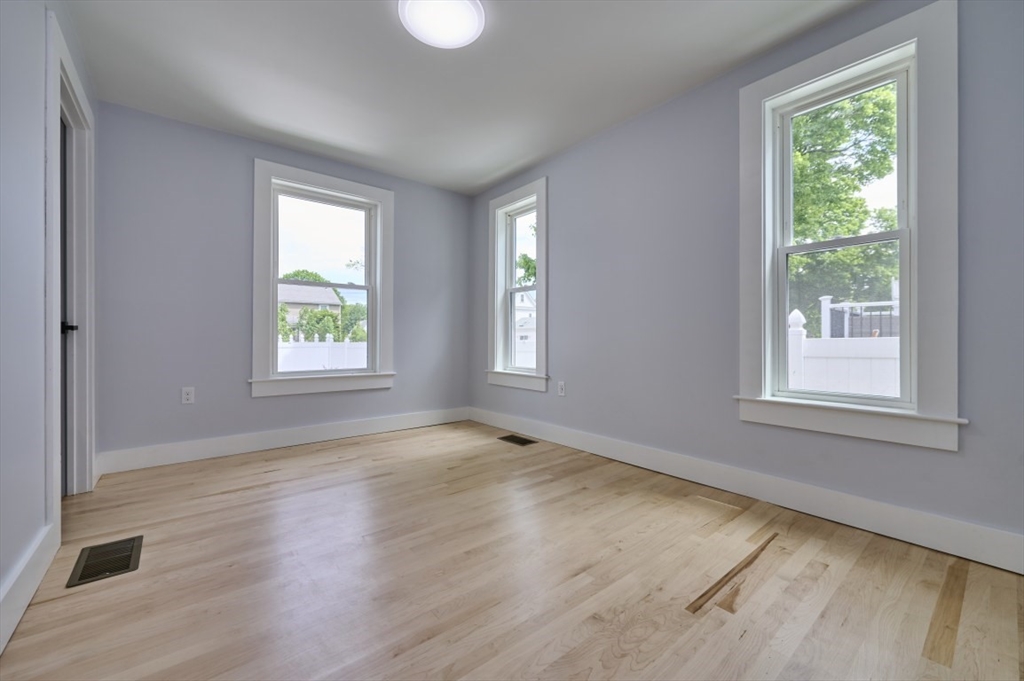 97 Oakton Avenue, Unit 1 Boston, MA 02122 - Photo 11 of 20 an empty room with wooden floor and windows