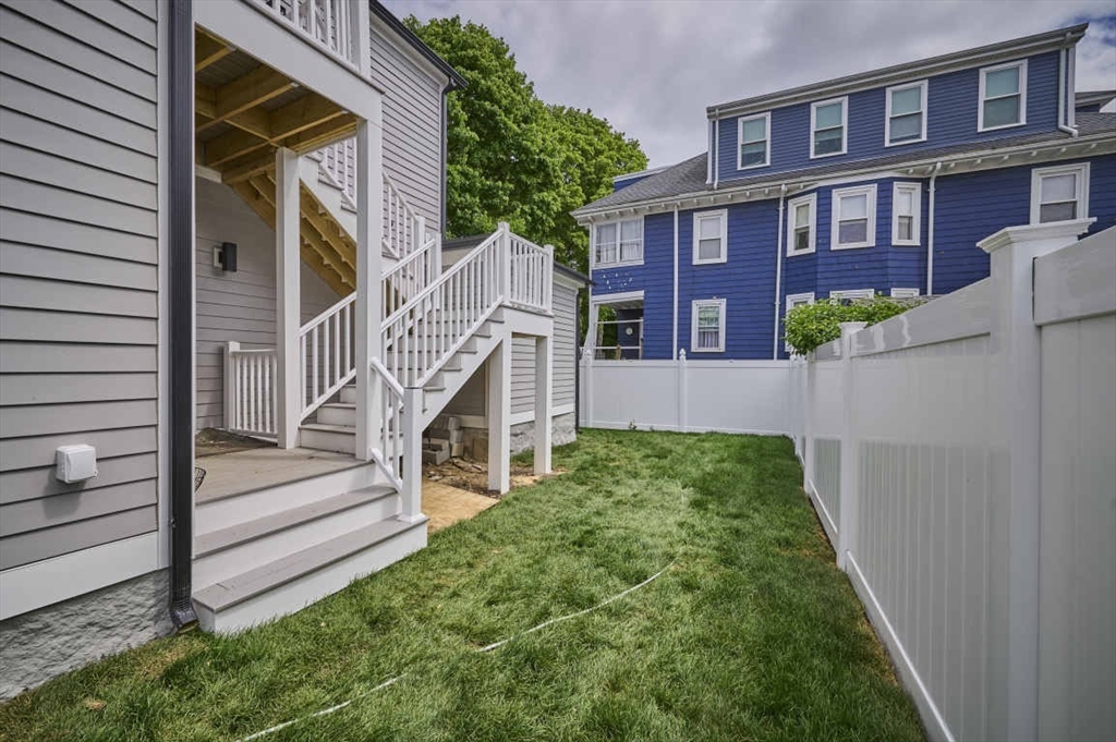 97 Oakton Avenue, Unit 1 Boston, MA 02122 - Photo 2 of 20 a view of a brick house with a small yard plants and wooden fence