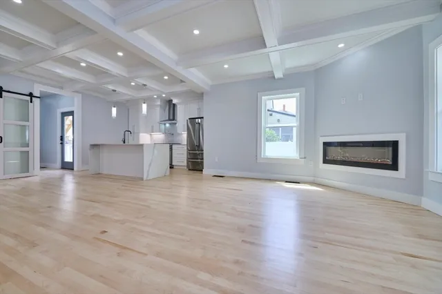 a view of an empty room with a kitchen and a window