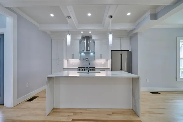 a view of a kitchen with kitchen island a sink wooden floor and stainless steel appliances