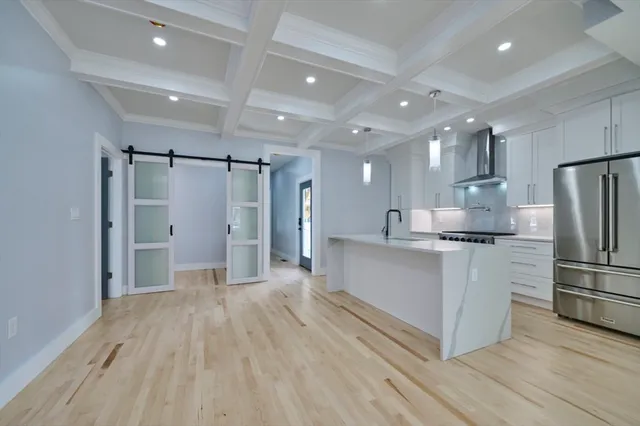 a large white kitchen with stainless steel appliances a refrigerator and a stove top oven