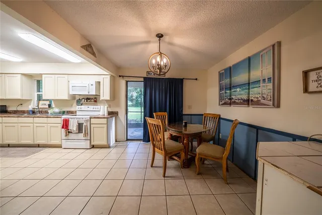 a kitchen with stainless steel appliances granite countertop a stove top oven a sink dishwasher a dining table and chairs with wooden floor