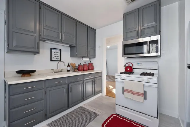 a kitchen with granite countertop white cabinets and stainless steel appliances